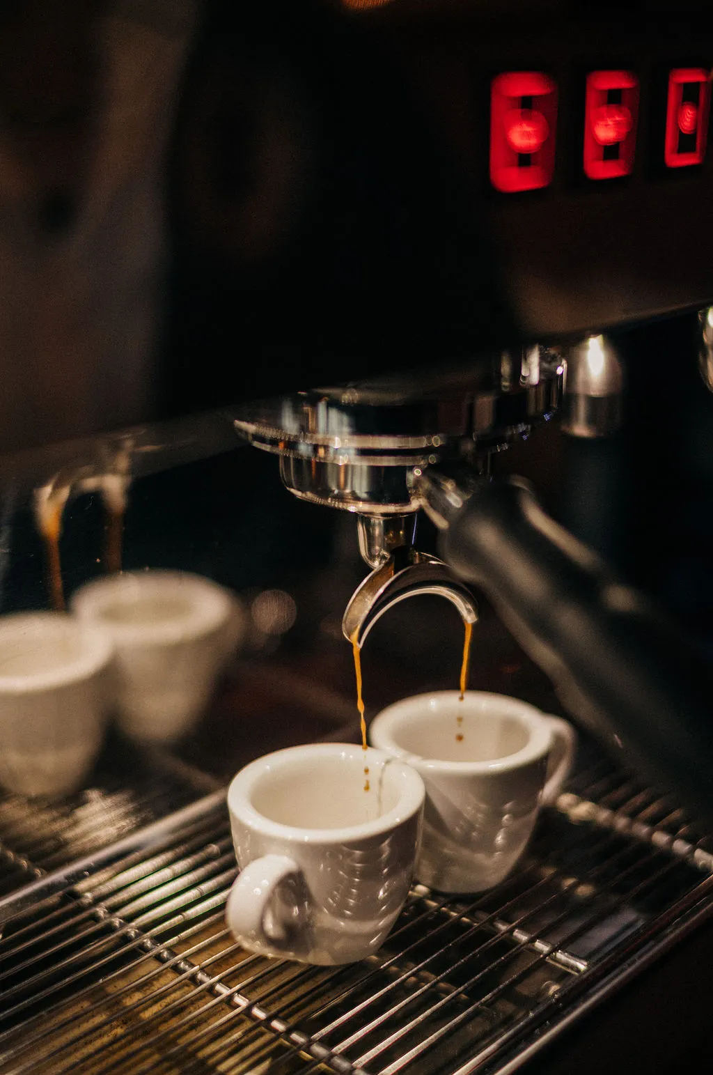Doppelter Espresso läuft aus dem Siebträger in zwei weiße Tassen