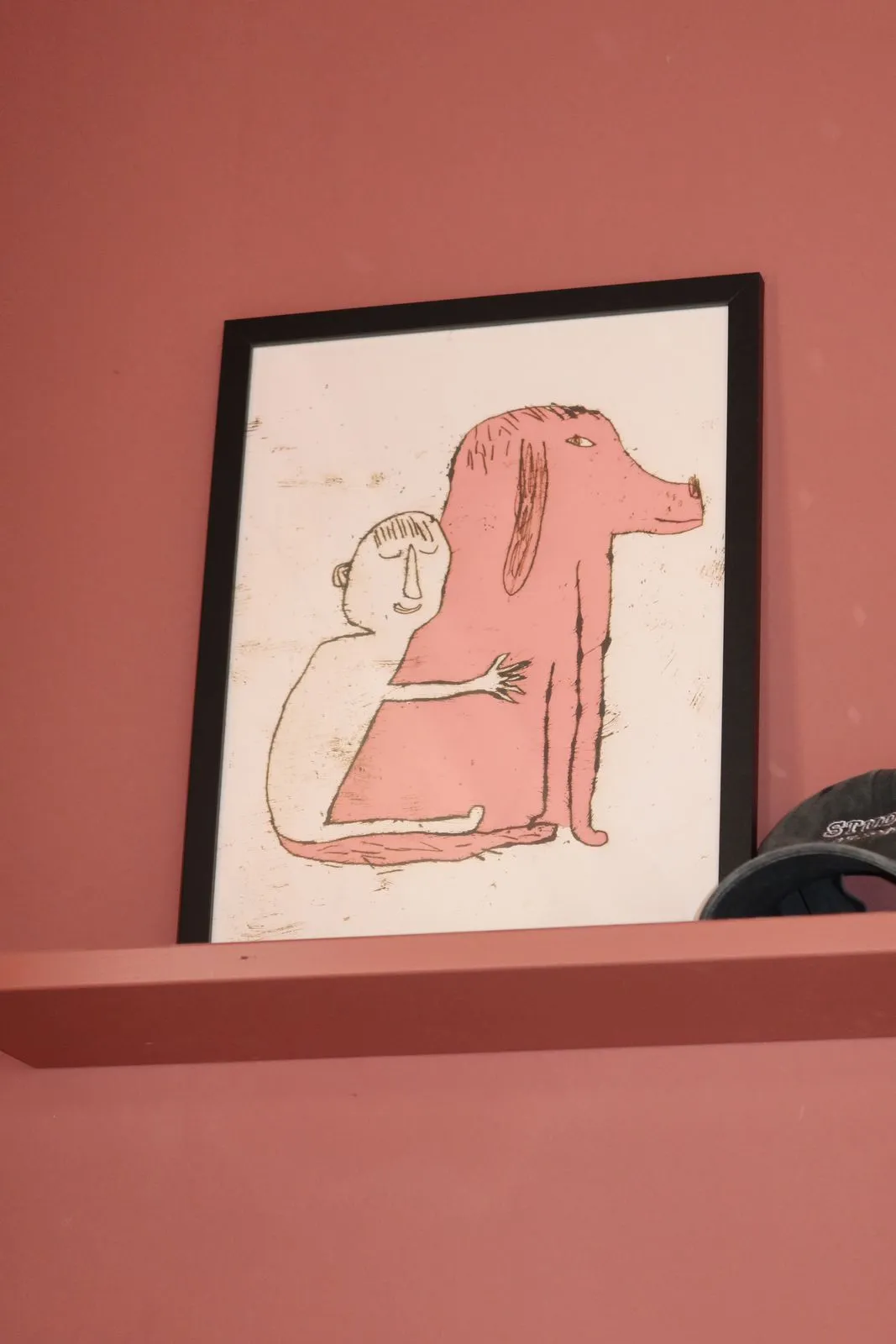 Gerahmte Zeichnung eines rosa Hundes auf einem Wandbrett